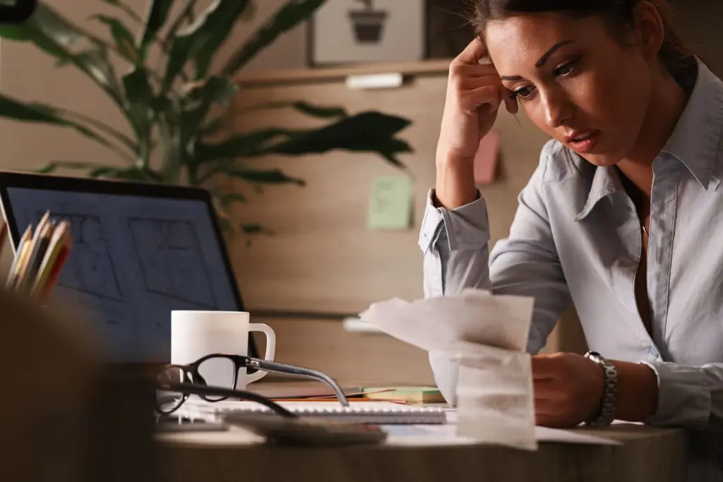 Mulher preocupada analisando contas e boletos, representando a frustração causada por cobranças indevidas e a busca por soluções jurídicas para resolver o problema.