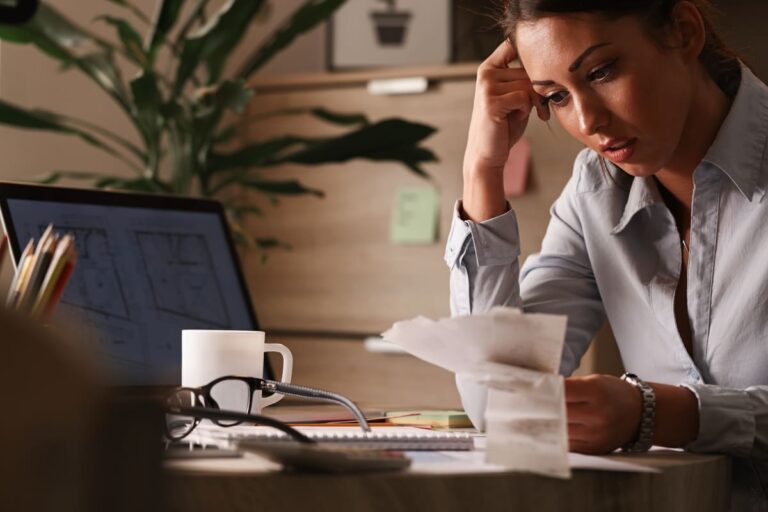 Mulher preocupada analisando contas e boletos, representando a frustração causada por cobranças indevidas e a busca por soluções jurídicas para resolver o problema.