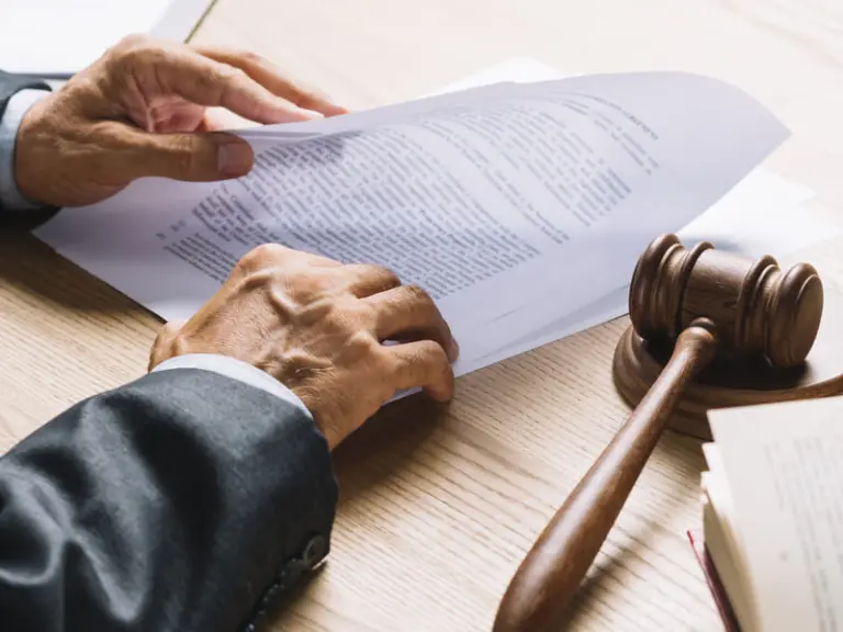 Advogado analisando documentos jurídicos com um martelo de juiz ao lado, representando a defesa criminal, atuação em processos penais e consultoria em Direito Criminal.